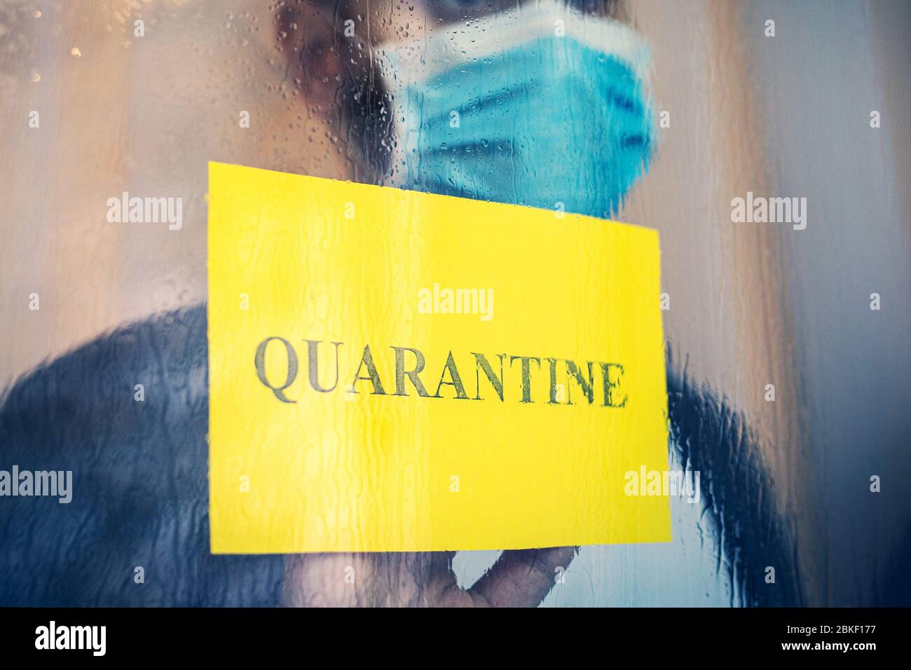 Mettere in quarantena il testo sulla finestra di avvertimento gialla. Uomo solitario con Coronavirus, Covid-19 in isolamento auto-quarantena in maschera medica protettiva a. Foto Stock