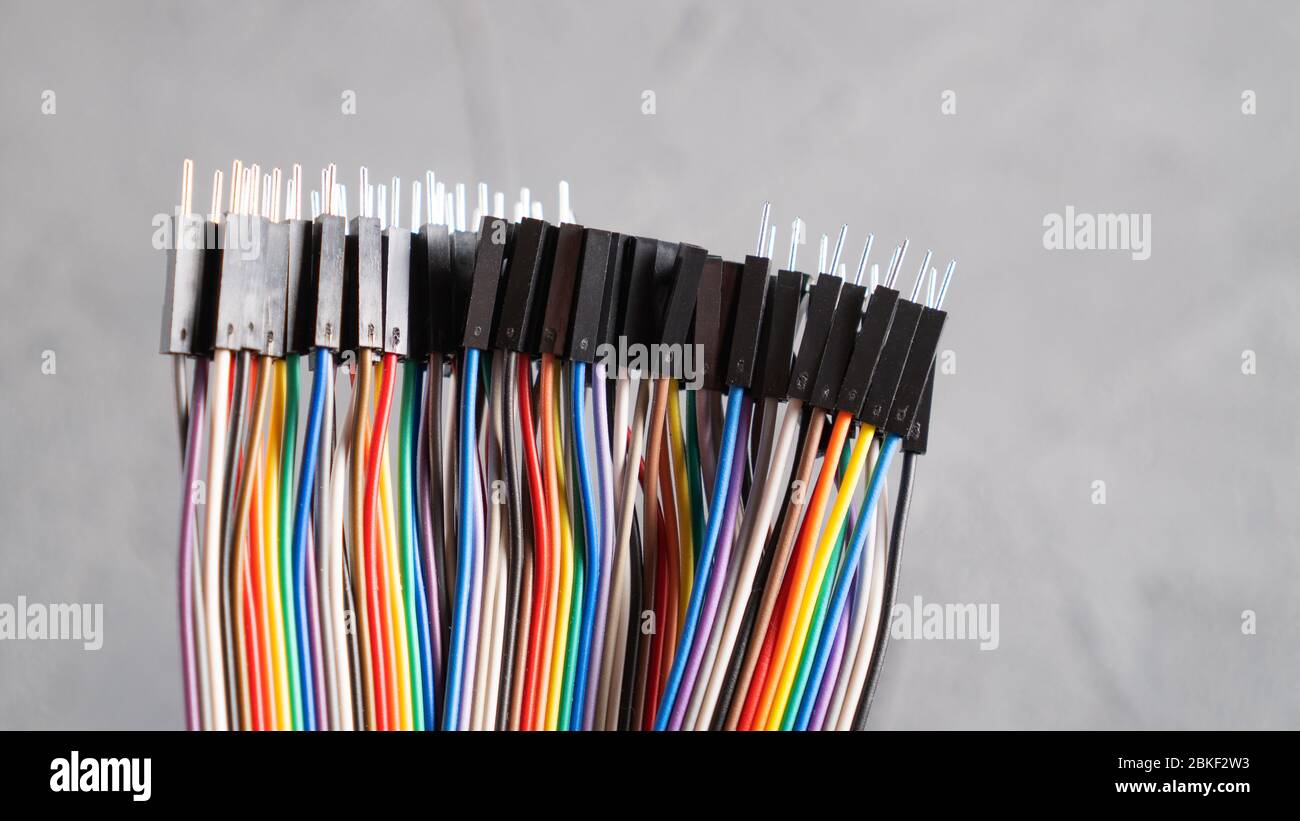 Connettori per ponticelli con punte di tipo diverso. Cavi colorati per circuito elettronico. Cavi arcobaleno su cemento Foto Stock
