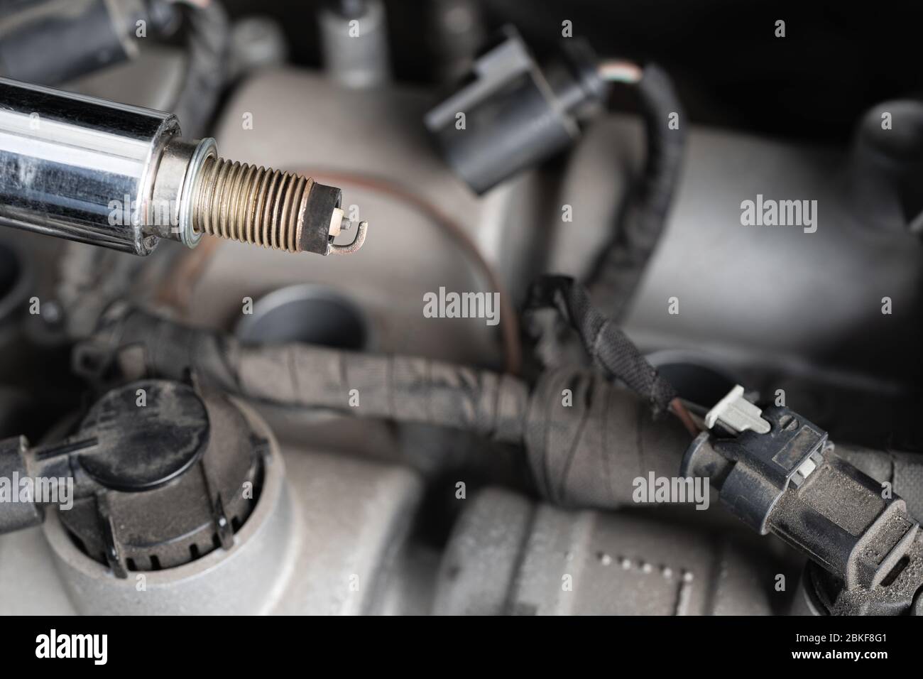 Chiave a bussola con candela usata nel vano motore per auto. Concetto di riparazione meccanica o manutenzione del veicolo. Foto Stock