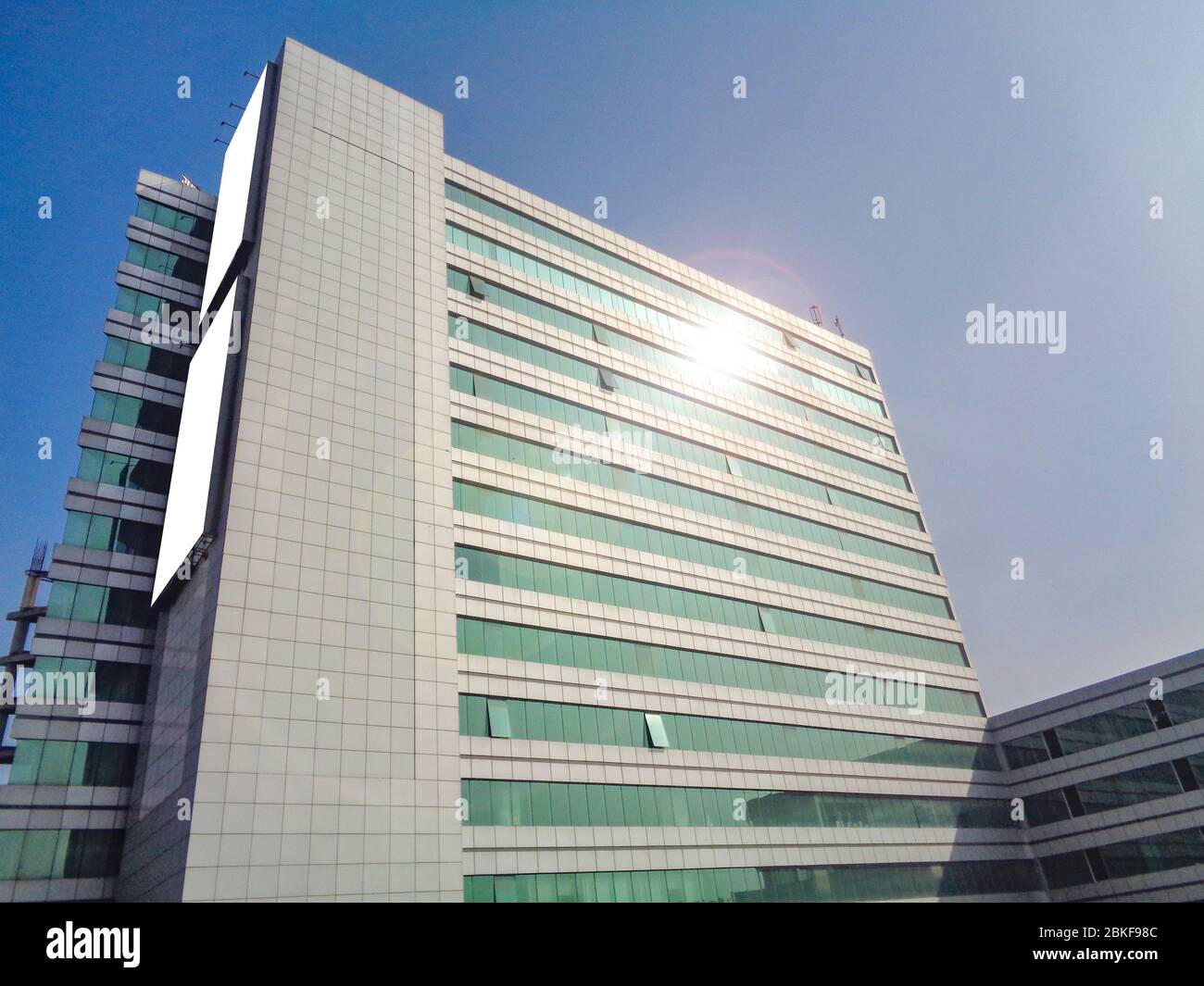Vista diagonale dell'edificio con un tabellone di affissione vuoto con riflessione lente-svasata Foto Stock