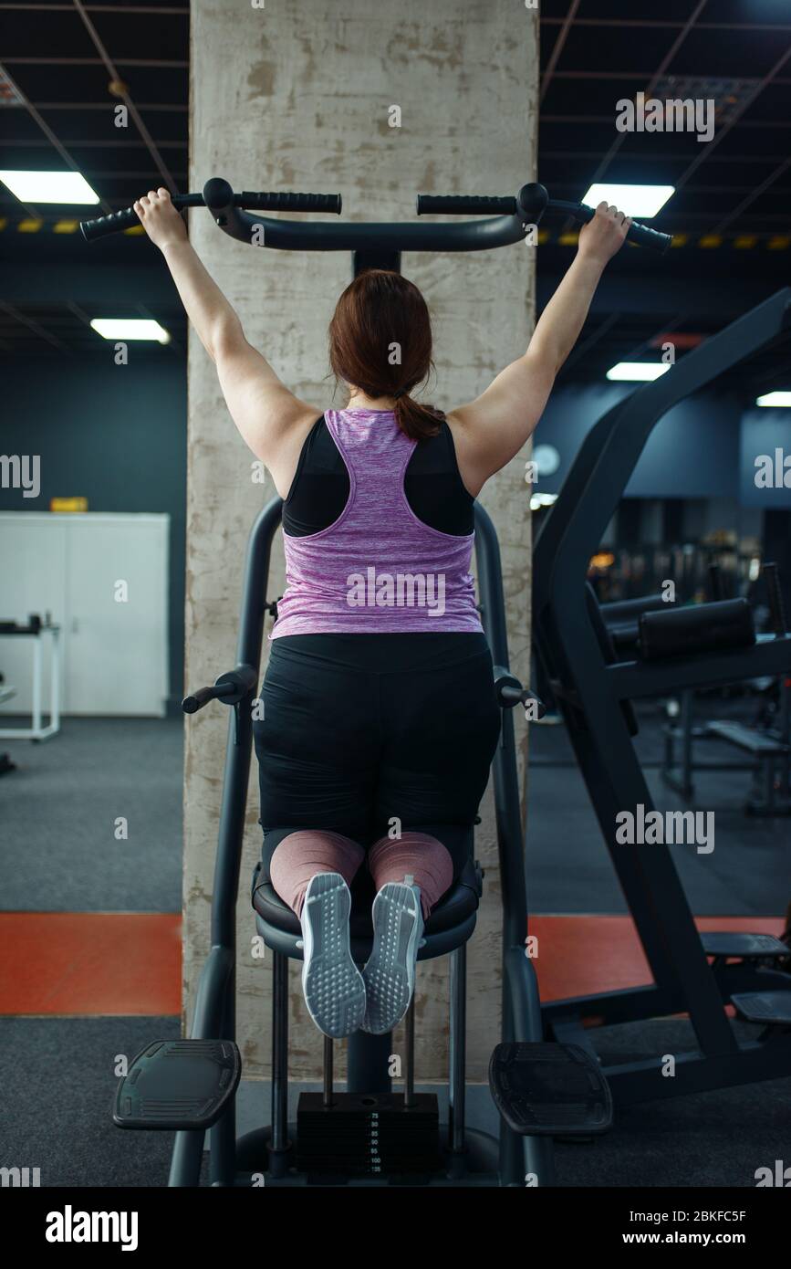 Donna in sovrappeso su macchina ginnica in palestra Foto Stock
