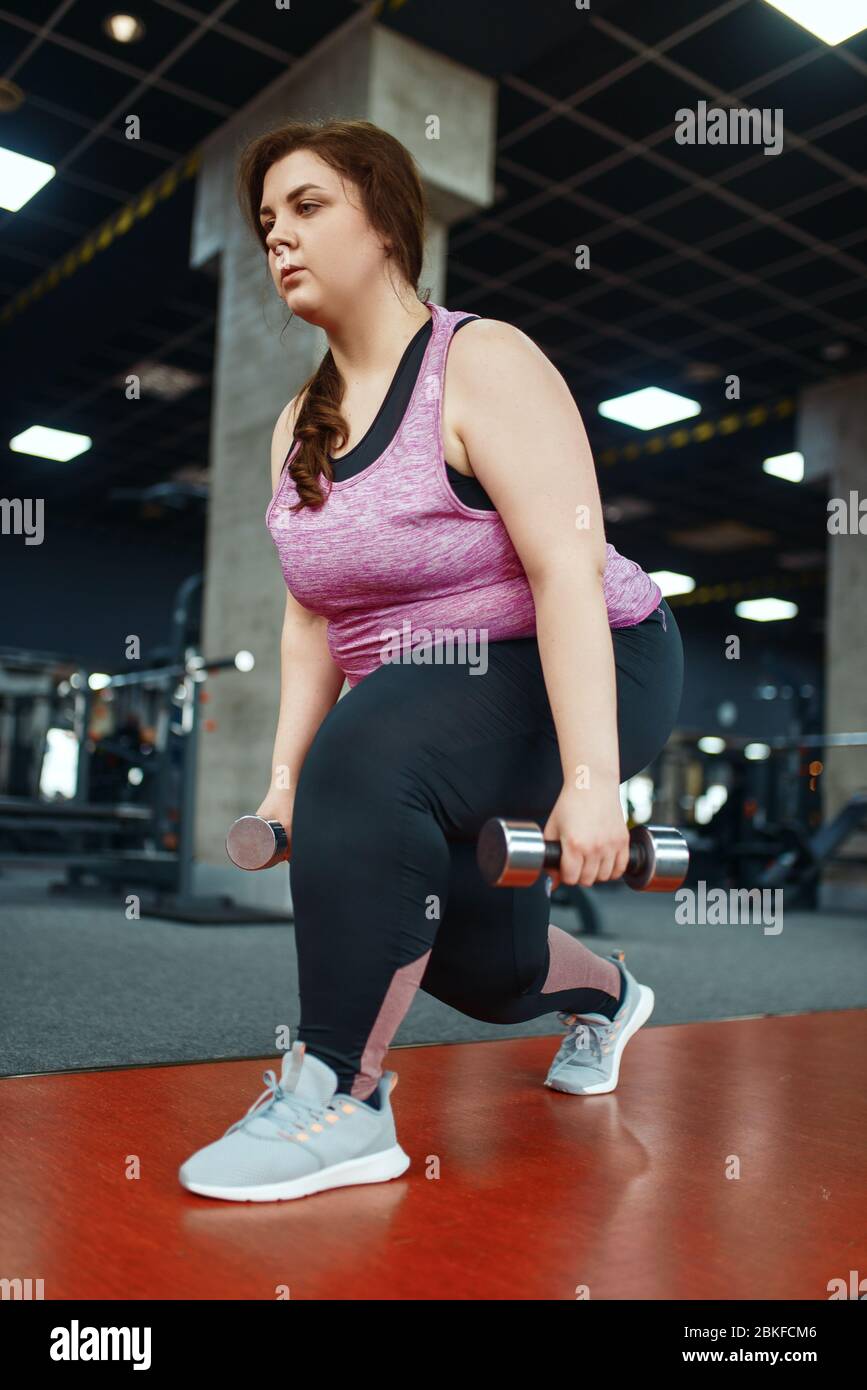 Donna sovrappeso, esercizio con manubri in palestra Foto Stock