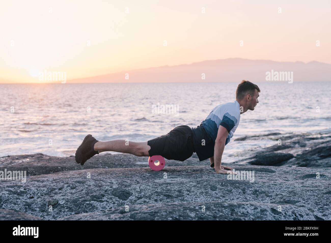 Uomo che fa auto massaggio del corpo con un rotolo. Formazione fascia Foto Stock