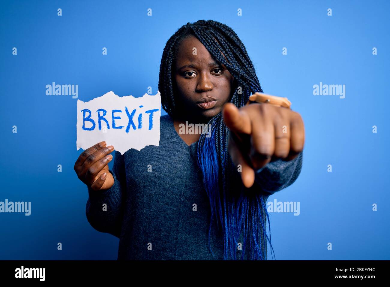 Giovane african american più donna con trecce tenere carta con messaggio brexit che punta con il dito alla fotocamera e a voi, segnale di mano, positiv Foto Stock
