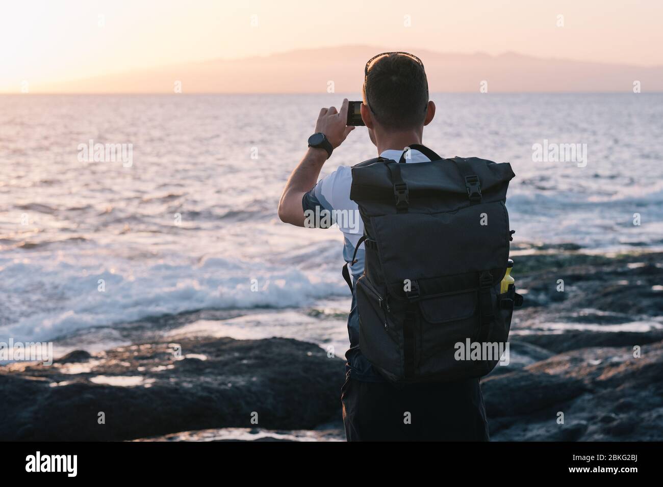 Uomo di scattare le foto del tramonto con il telefono cellulare Foto Stock