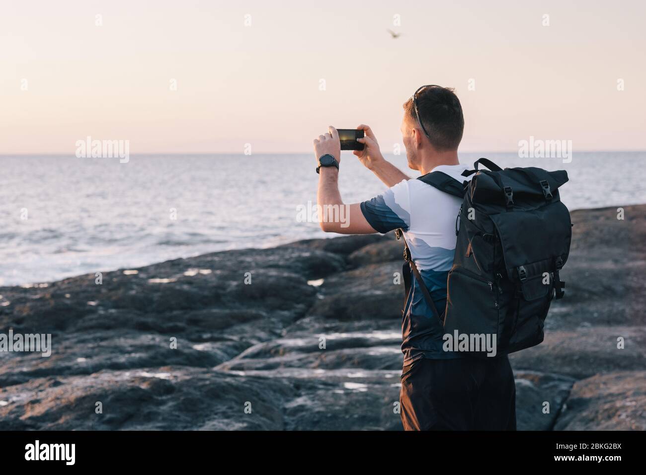 Uomo di scattare le foto del tramonto con il telefono cellulare Foto Stock