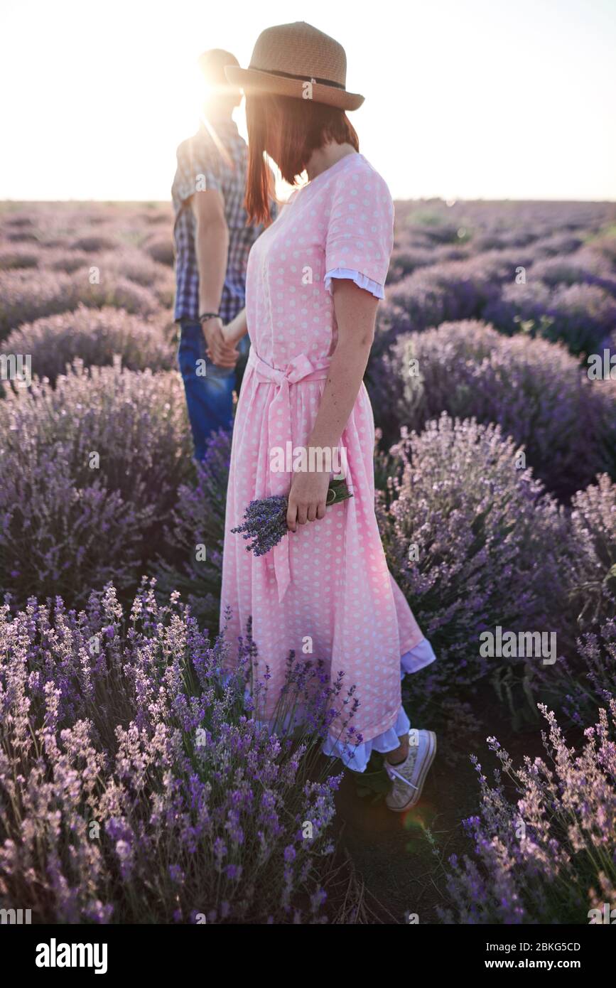 Coppia innamorata. Giovane ragazza in abito romantico e uomo nei campi di lavanda Foto Stock