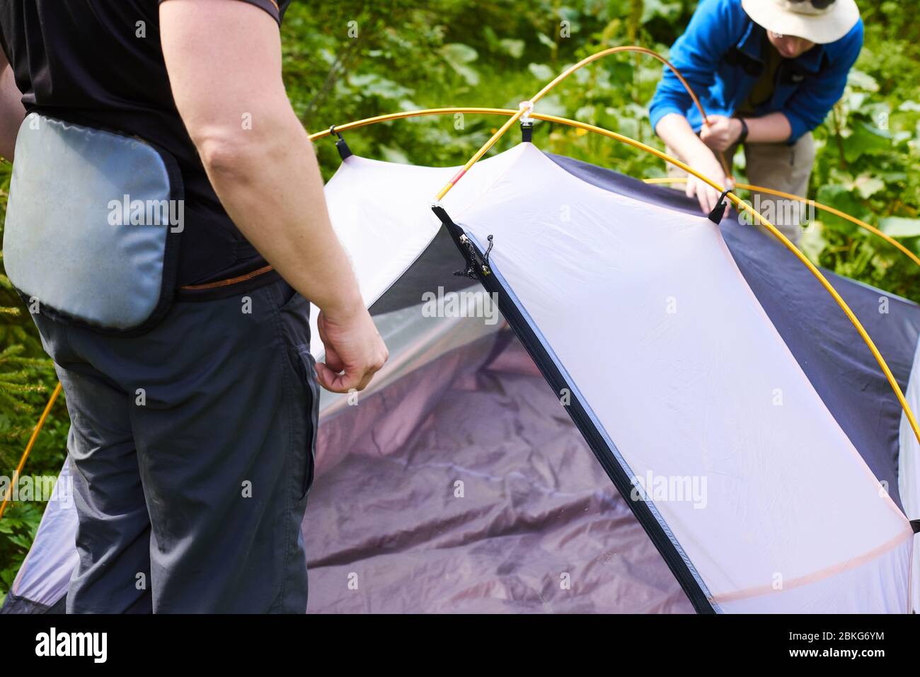 giornata del turismo. turisti - due uomini in abiti turistici e con attrezzature speciali - mettere una tenda in un campeggio. Foto Stock