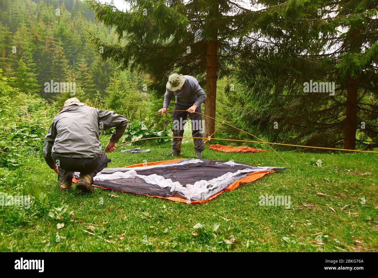 giornata del turismo. turisti - due uomini in abiti turistici e con attrezzature speciali - mettere una tenda in un campeggio. Foto Stock