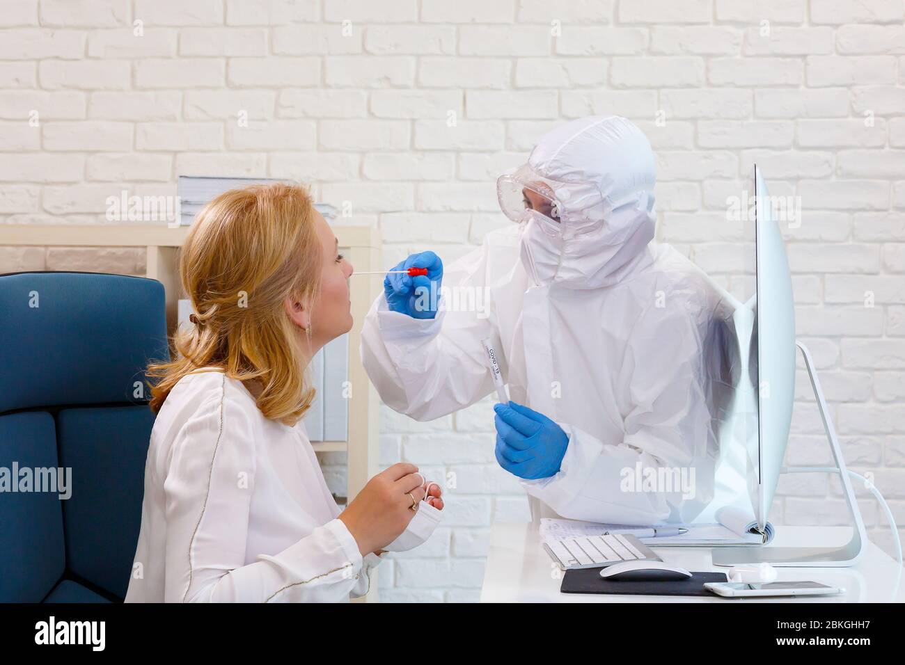 Woman Doctor è testato per Covid-19 Coronavirus presso l'ufficio medico dell'ospedale durante la realizzazione di una ricerca sul computer. Infermiere in una completa su protettiva Foto Stock