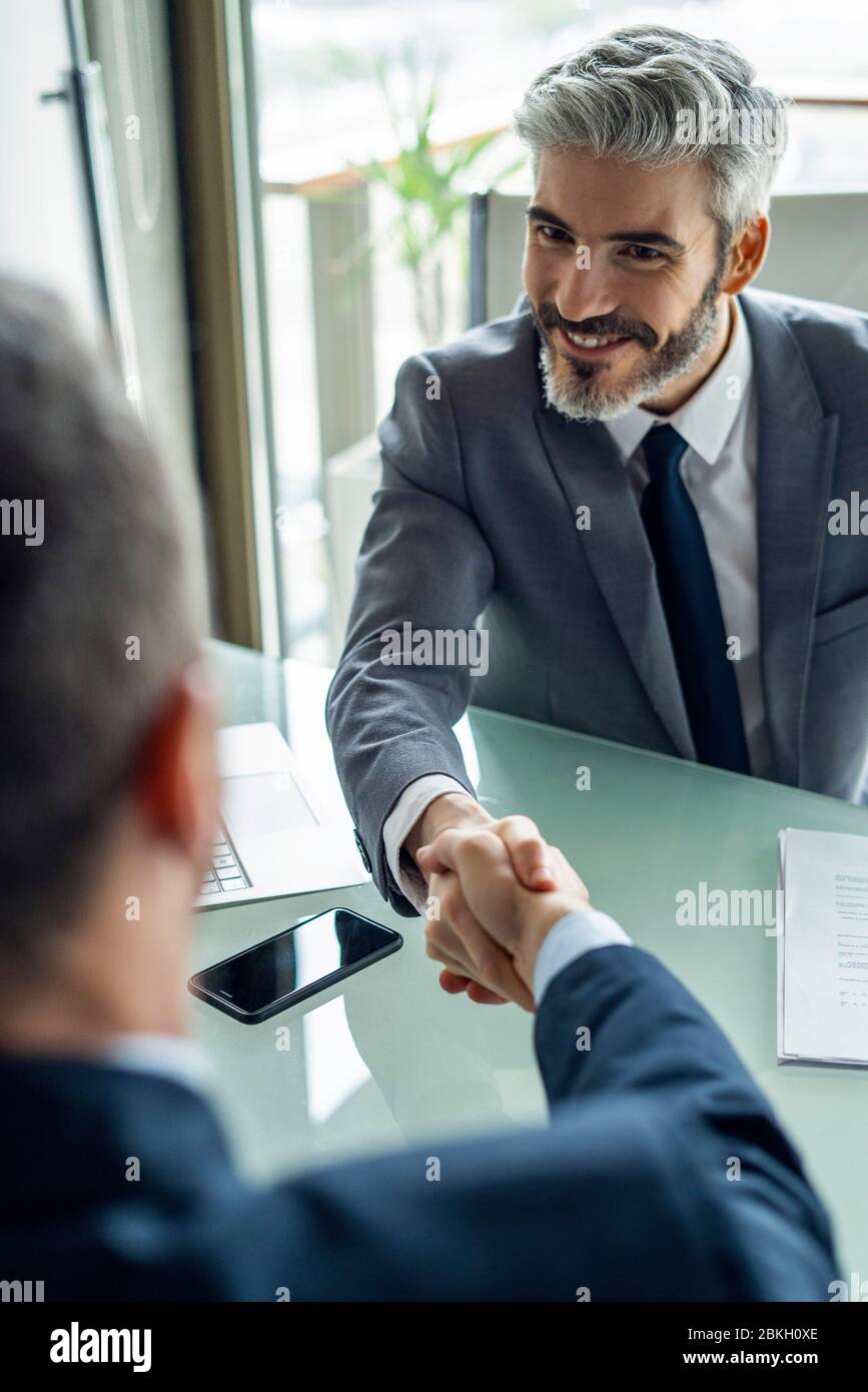 Uomini d'affari si stringono la mano in ufficio Foto Stock