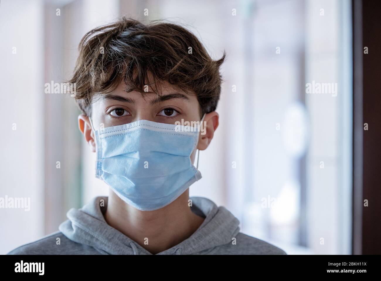 Primo piano di ragazzo adolescente che indossa maschera chirurgica blu Foto Stock
