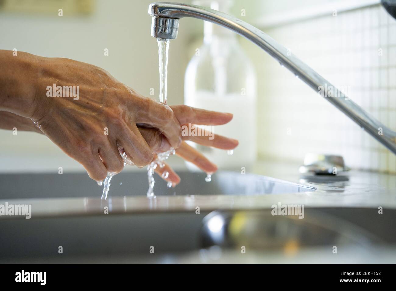 Uomo lavando le mani con acqua nel lavandino del bagno Foto Stock