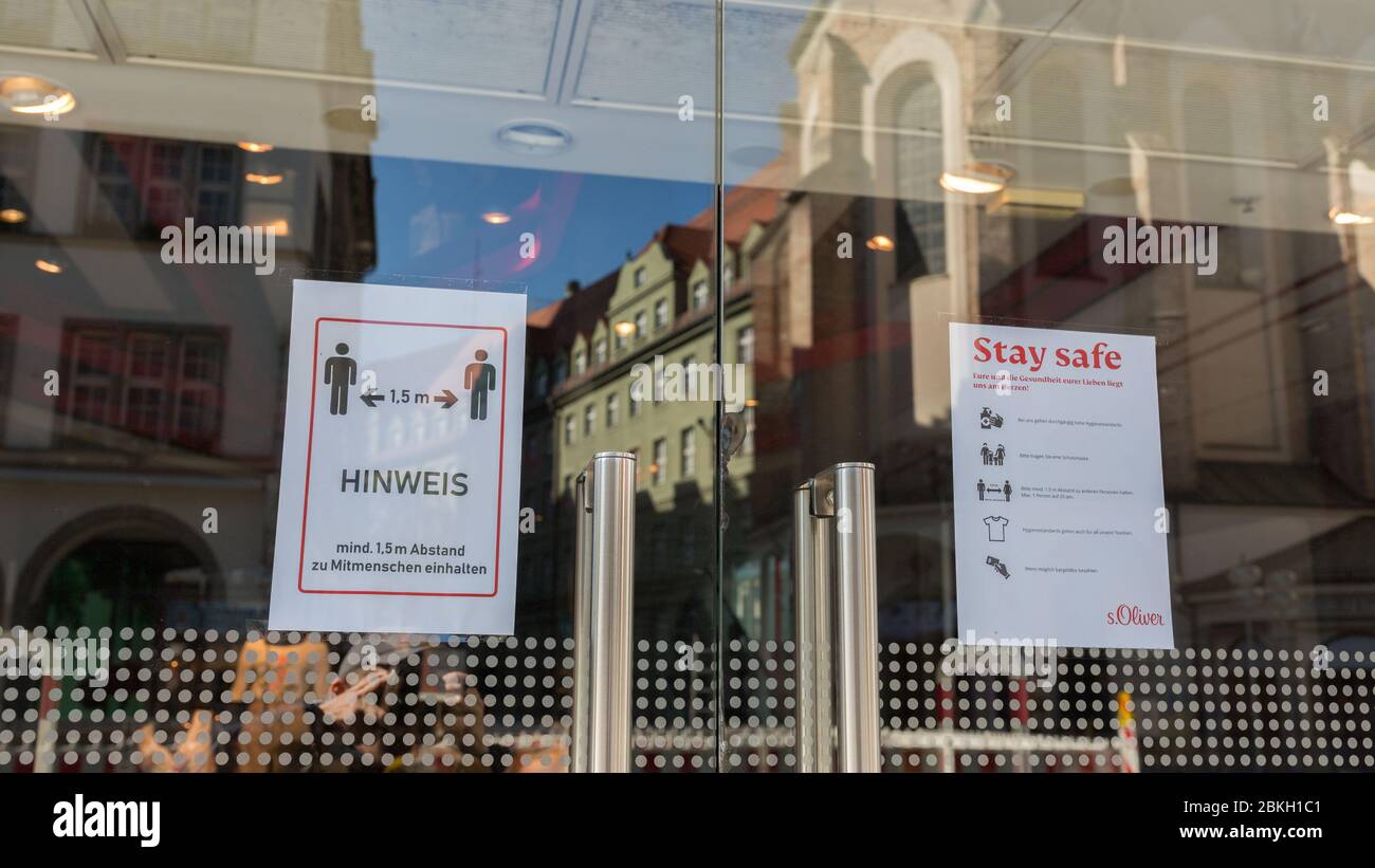 Cartelli con norme di sicurezza Covid-19 all'ingresso di un negozio nella zona pedonale di Monaco (Neuhauser Straße). Con vetro riflesso di case. Foto Stock