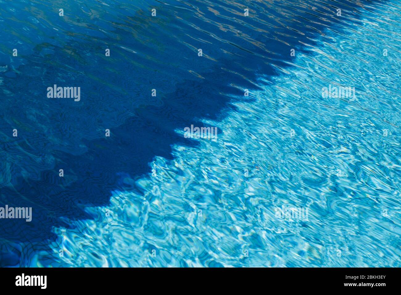 A due luci colorate e blu scuro acqua con increspature e riflessi di sole in una piscina. Foto Stock