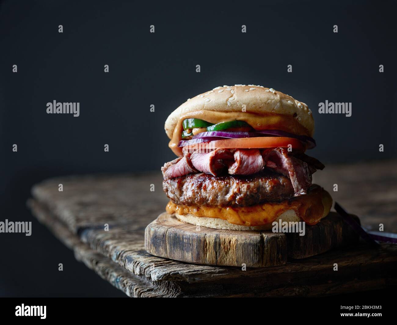 hamburger di bistecca fresco e gustoso su vecchio tavolo di legno Foto Stock