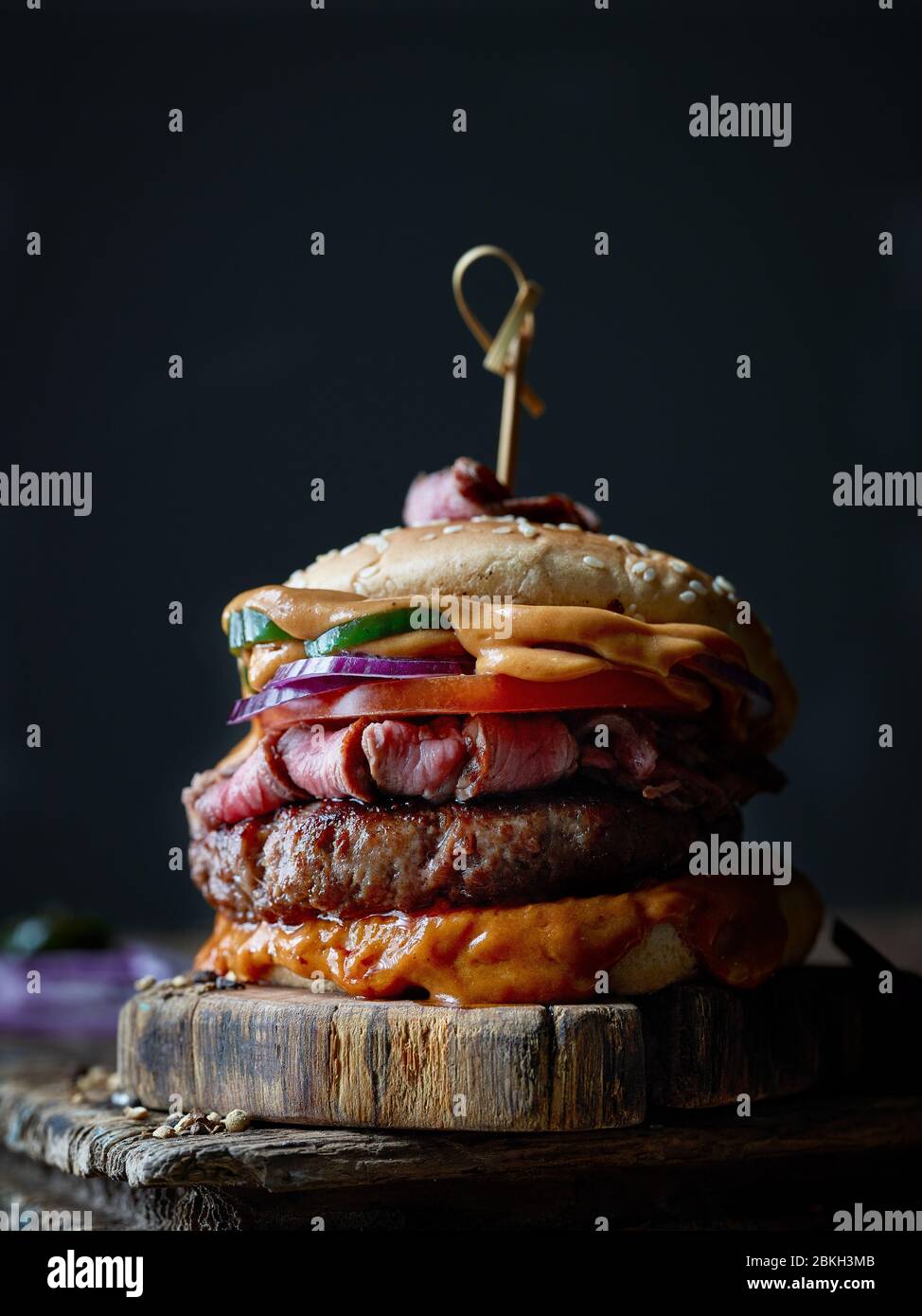 hamburger di bistecca fresco e gustoso su vecchio tavolo di legno Foto Stock