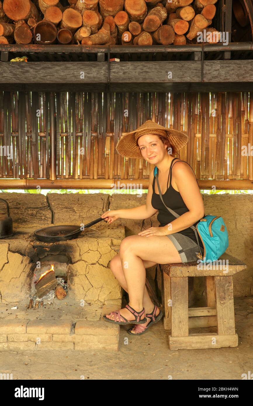 Giovane donna che arrostona i chicchi di caffè in una padella di ghisa. Utilizzando metodi tradizionali in una piantagione di caffè fattoria a Bali, Indonesia, Asia. Preparazione del caffè Foto Stock