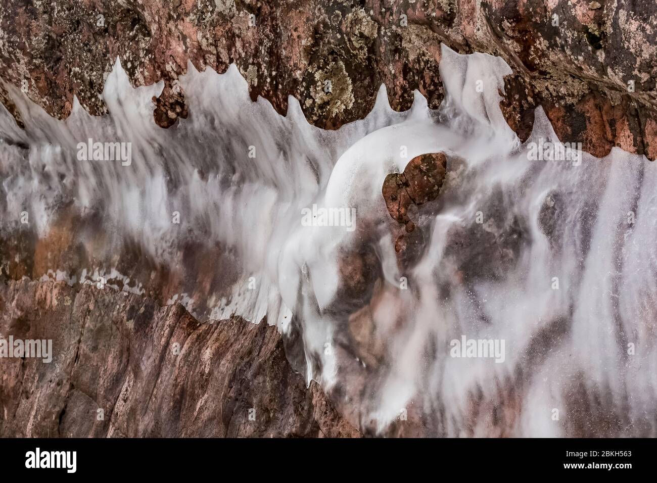 Tende di ghiaccio sulla superficie delle scogliere del Tettegouche state Park, dove le onde del Lago Superior si schiantano contro la roccia, lasciando uno strato d'acqua che libera Foto Stock