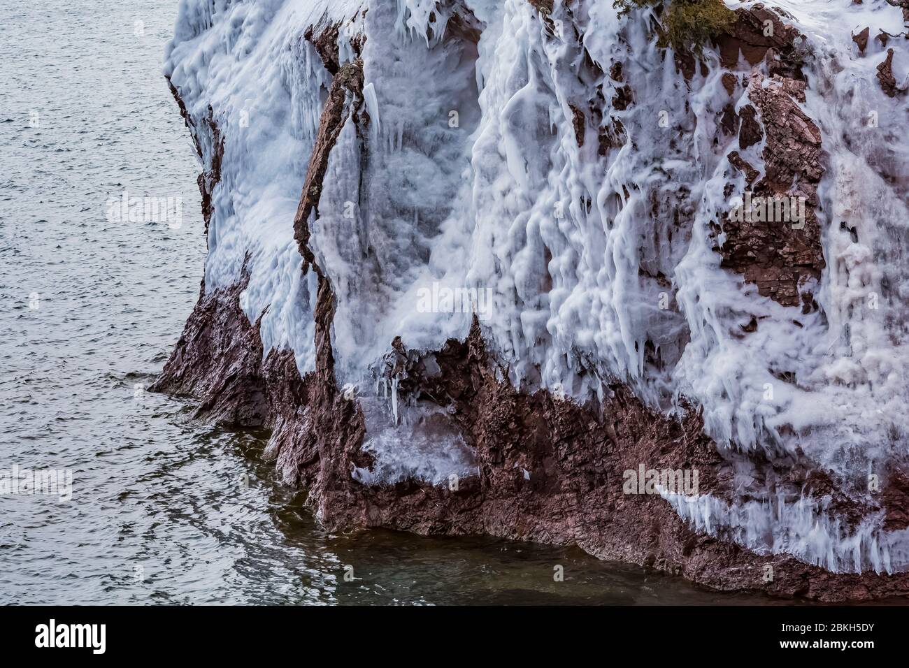 Tende di ghiaccio sulla superficie delle scogliere del Tettegouche state Park, dove le onde del Lago Superior si schiantano contro la roccia, lasciando uno strato d'acqua che libera Foto Stock