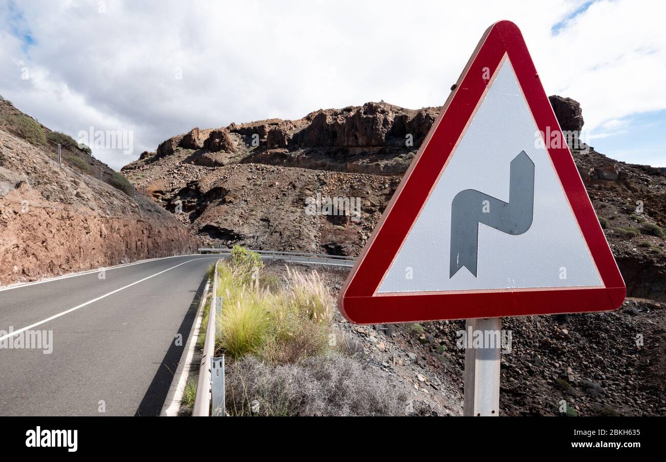 Segnale di avvertimento: Curva in strada. Un cartello stradale triangolare che dà l'avviso di una curva davanti all'autostrada. Foto Stock