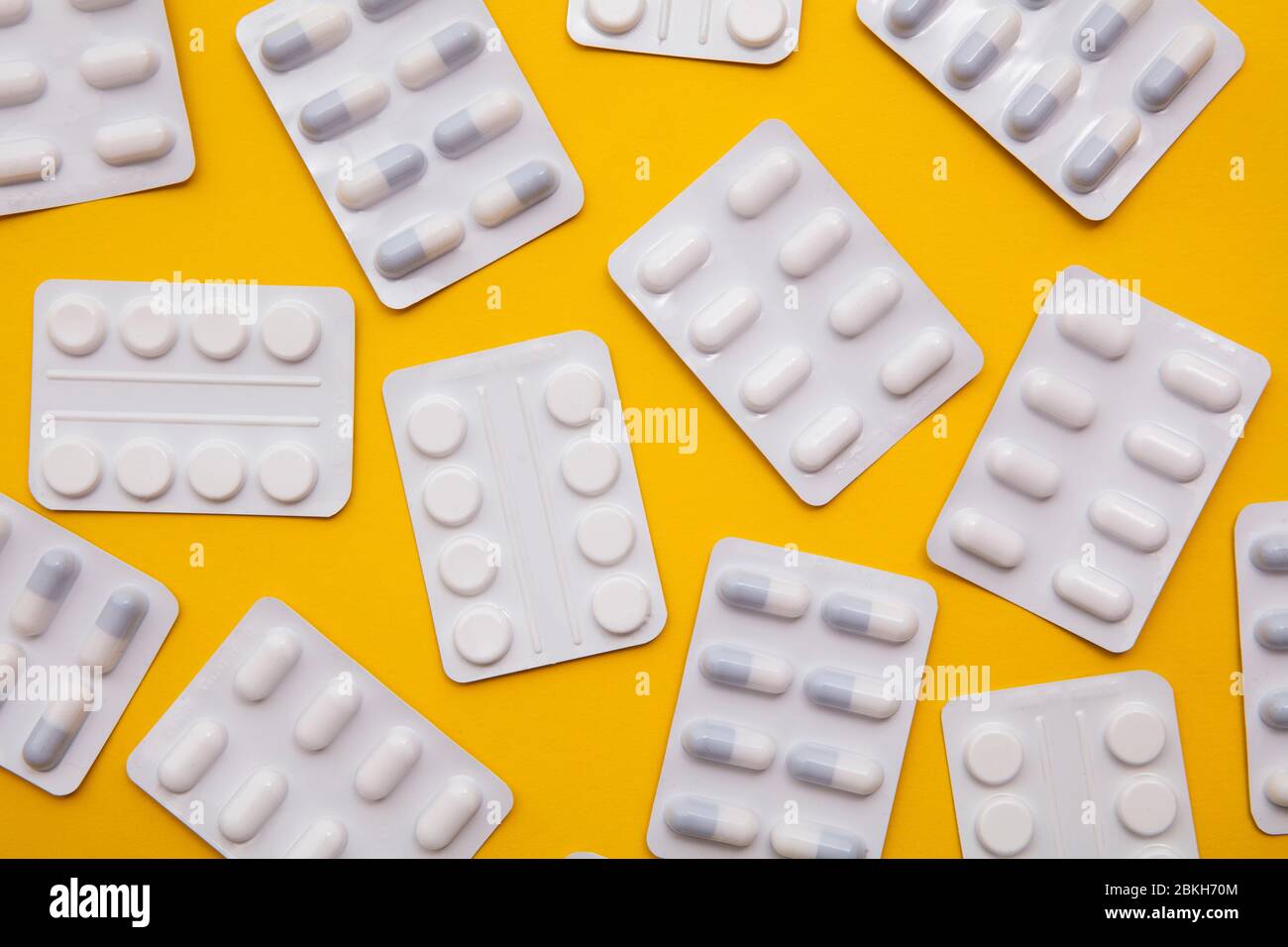 pacchetti di pillole e compresse per farmaci su sfondo giallo brillante Foto Stock