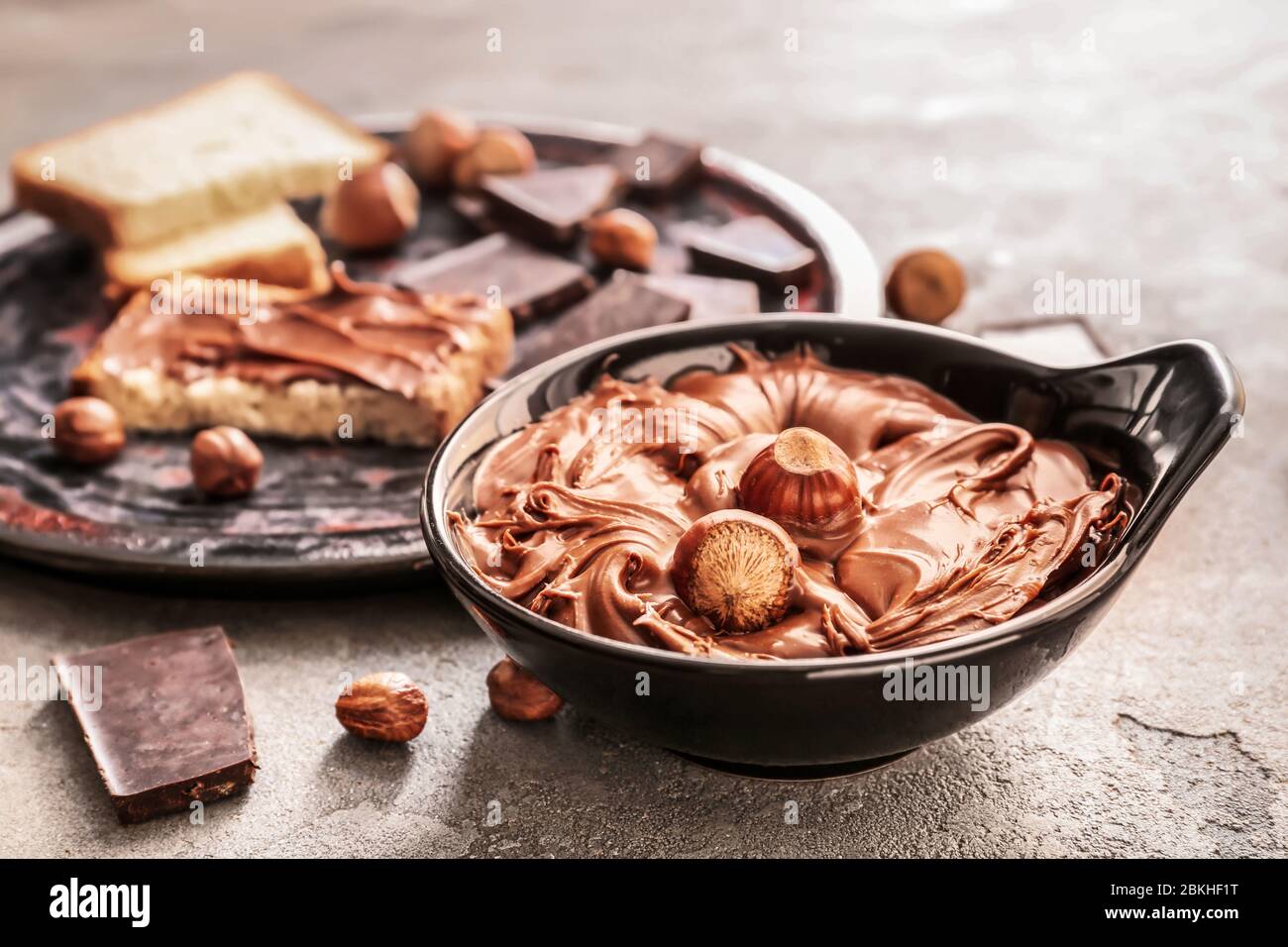 Ciotola con gustosa pasta di cioccolato e nocciole su fondo grunge Foto  stock - Alamy