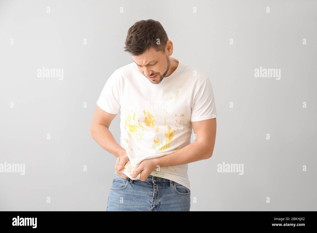 L'uomo si è dispiaciuto in vestiti sporchi su sfondo chiaro Foto Stock