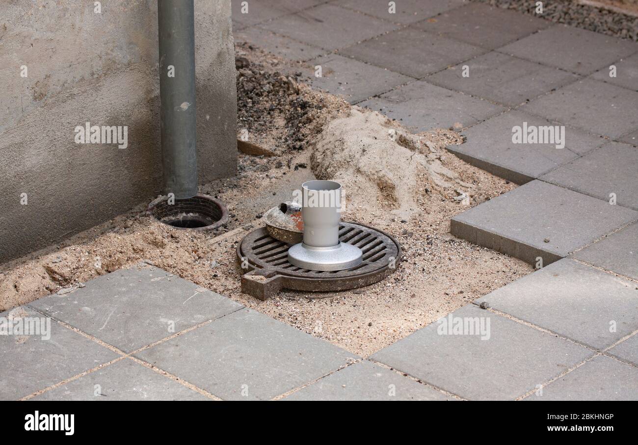 Prolunghe e riparazioni del tubo di scarico per un migliore drenaggio in connessione con l'esterno giardino piastrelle. Foto Stock