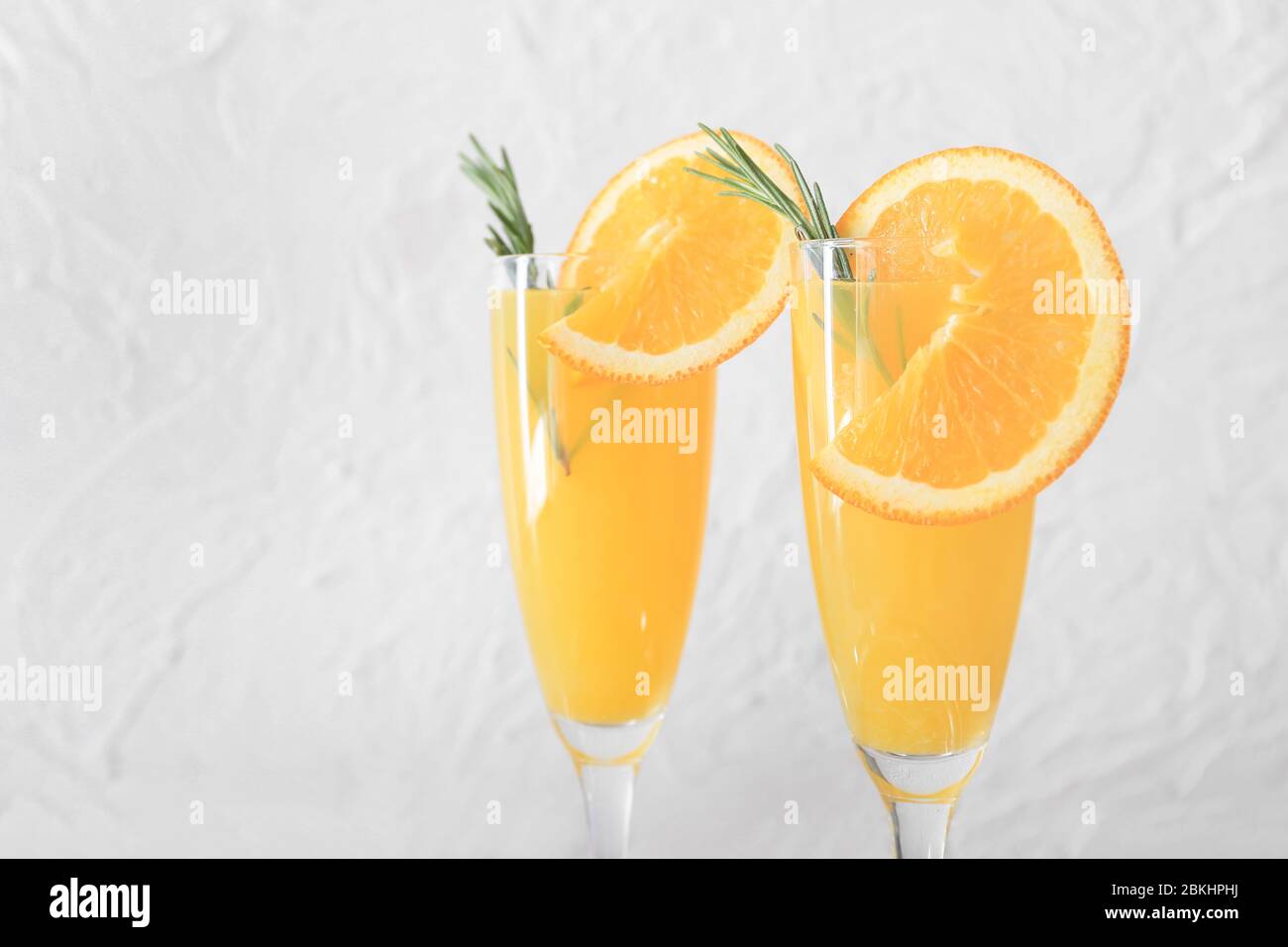 Bicchieri di gustosi cocktail mimosa su sfondo chiaro Foto Stock