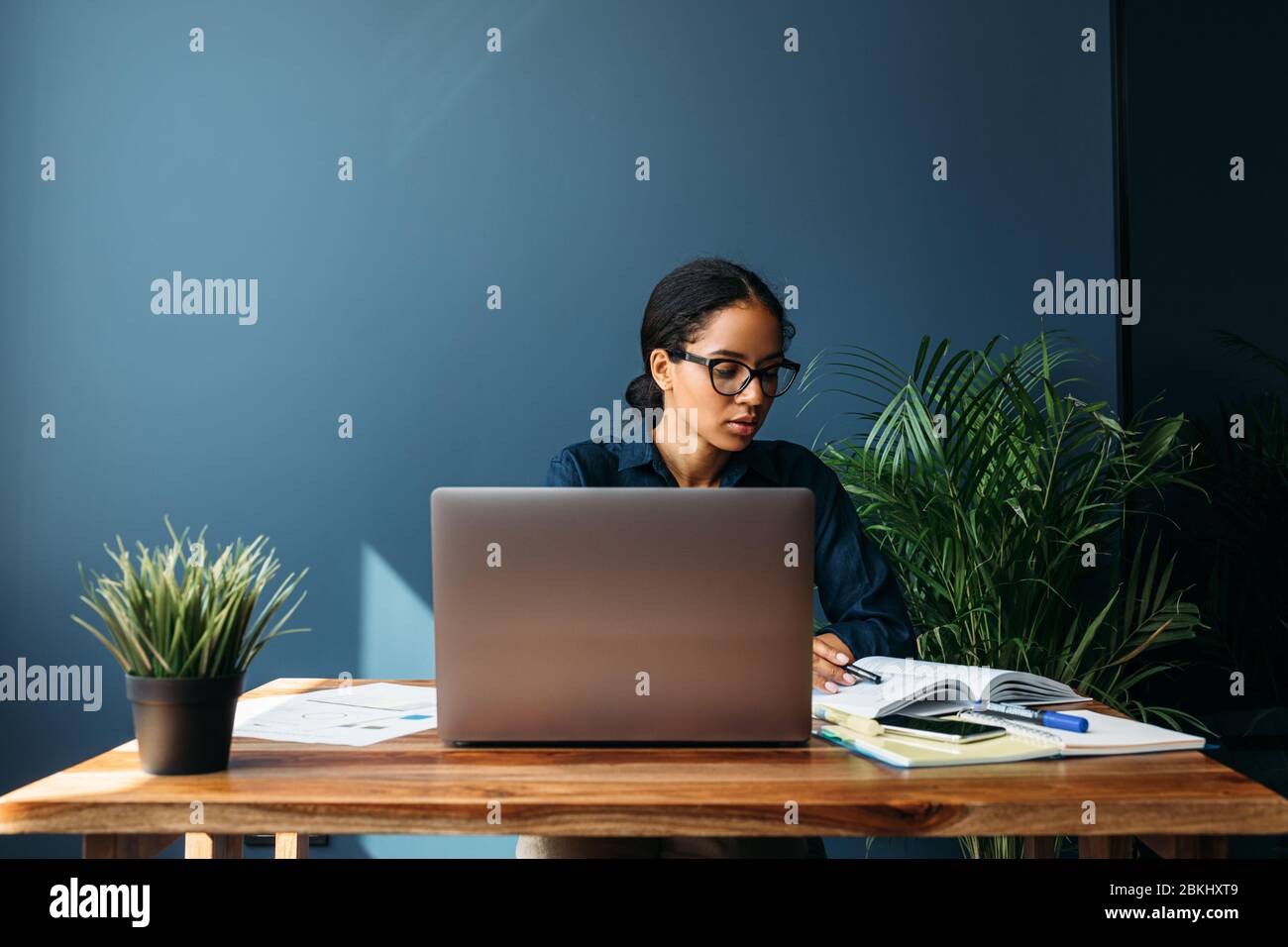 Giovane donna attenta che guarda i documenti in ufficio. Imprenditore che lavora in remoto. Foto Stock