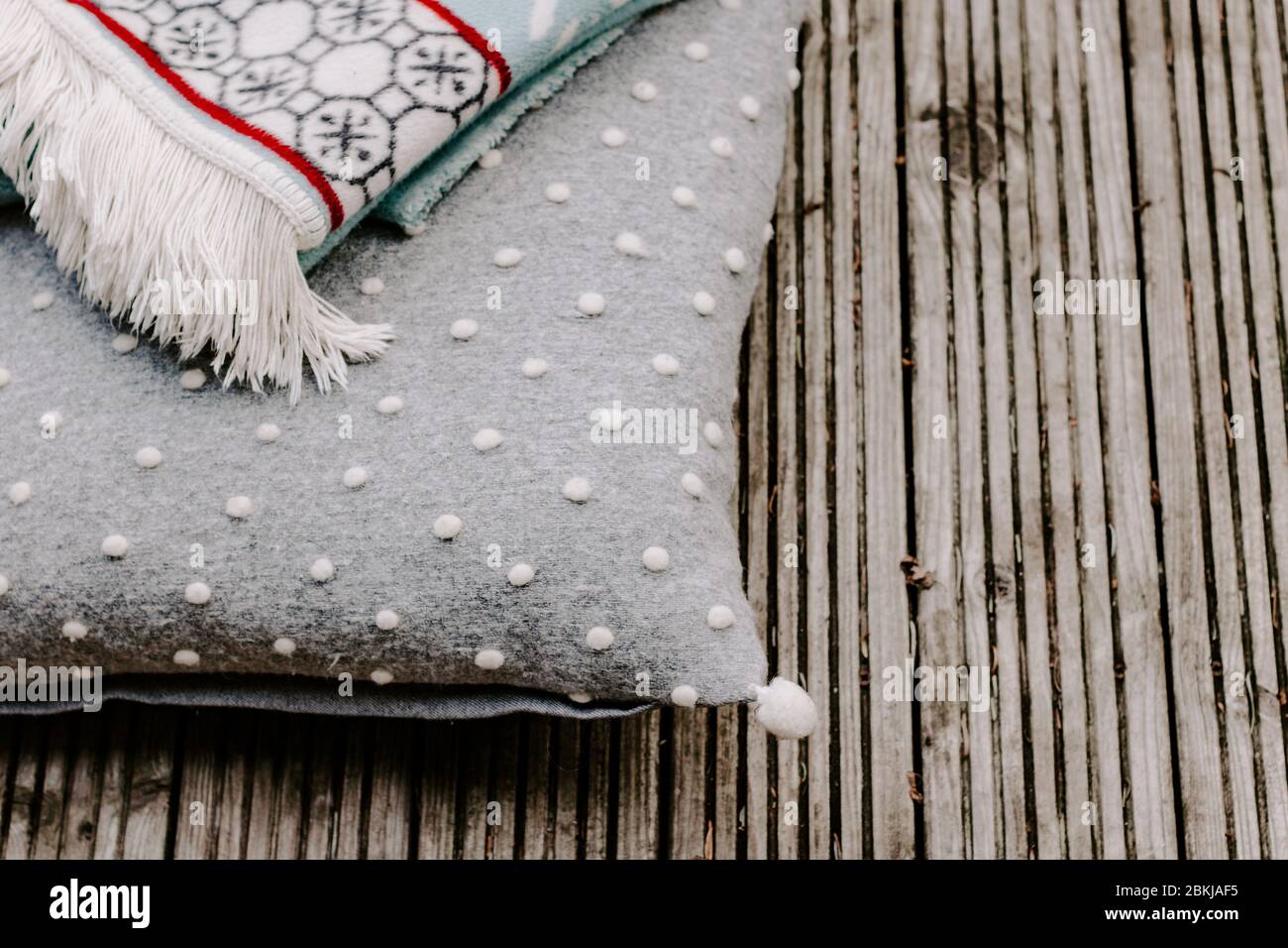 Coperta con frange, cuscino grigio, coperta in legno, concetto di casa, casalinga, calore, hygge, fibre naturali, coperte, concetto di inverno, calore, casa, casa Foto Stock