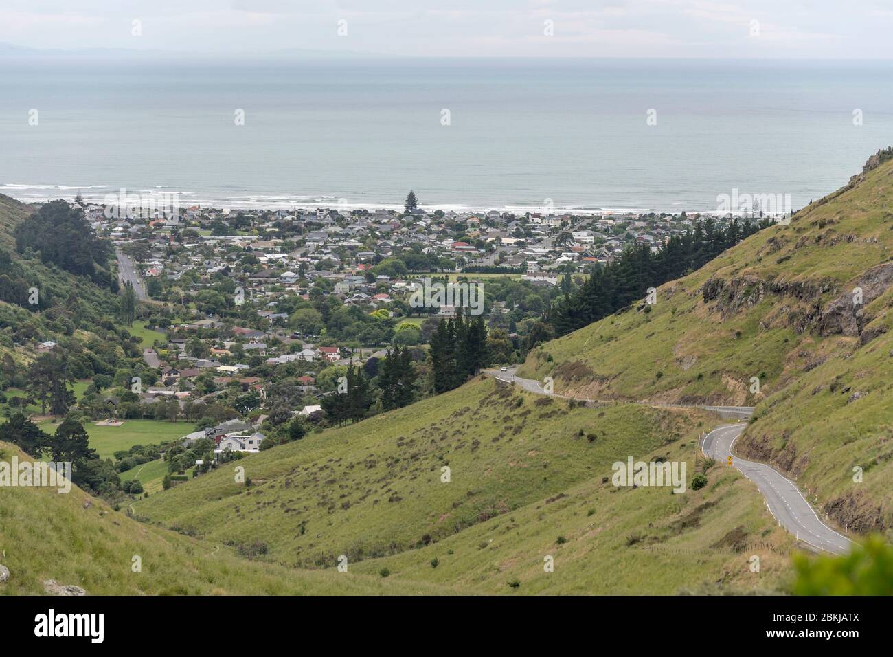 Strada tortuosa su verdi colline intorno a Sumner Bborough sulla riva dell'oceano, sparato in luce nuvolosa, Christchurch, South Island, Nuova Zelanda Foto Stock