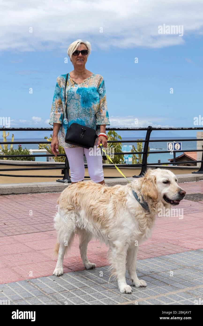 Una donna che cammina il suo cane labrador durante il covid 19 lockdown nella zona turistica di Costa Adeje, Tenerife, Isole Canarie, Spagna Foto Stock