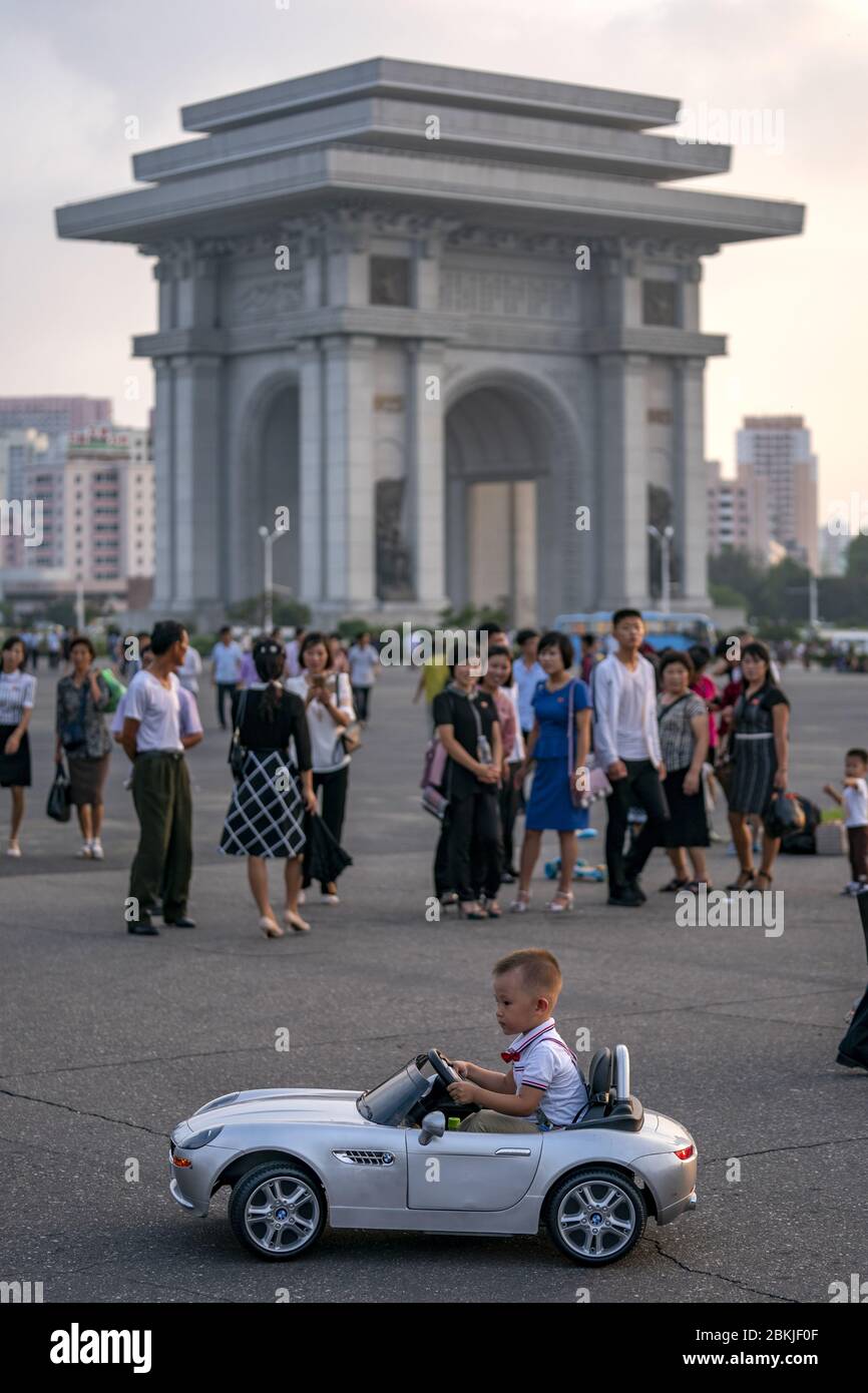 Corea del Nord, Pyongyang, bambino che gioca con una BMW cablati davanti all'Arco di Trionfo Foto Stock