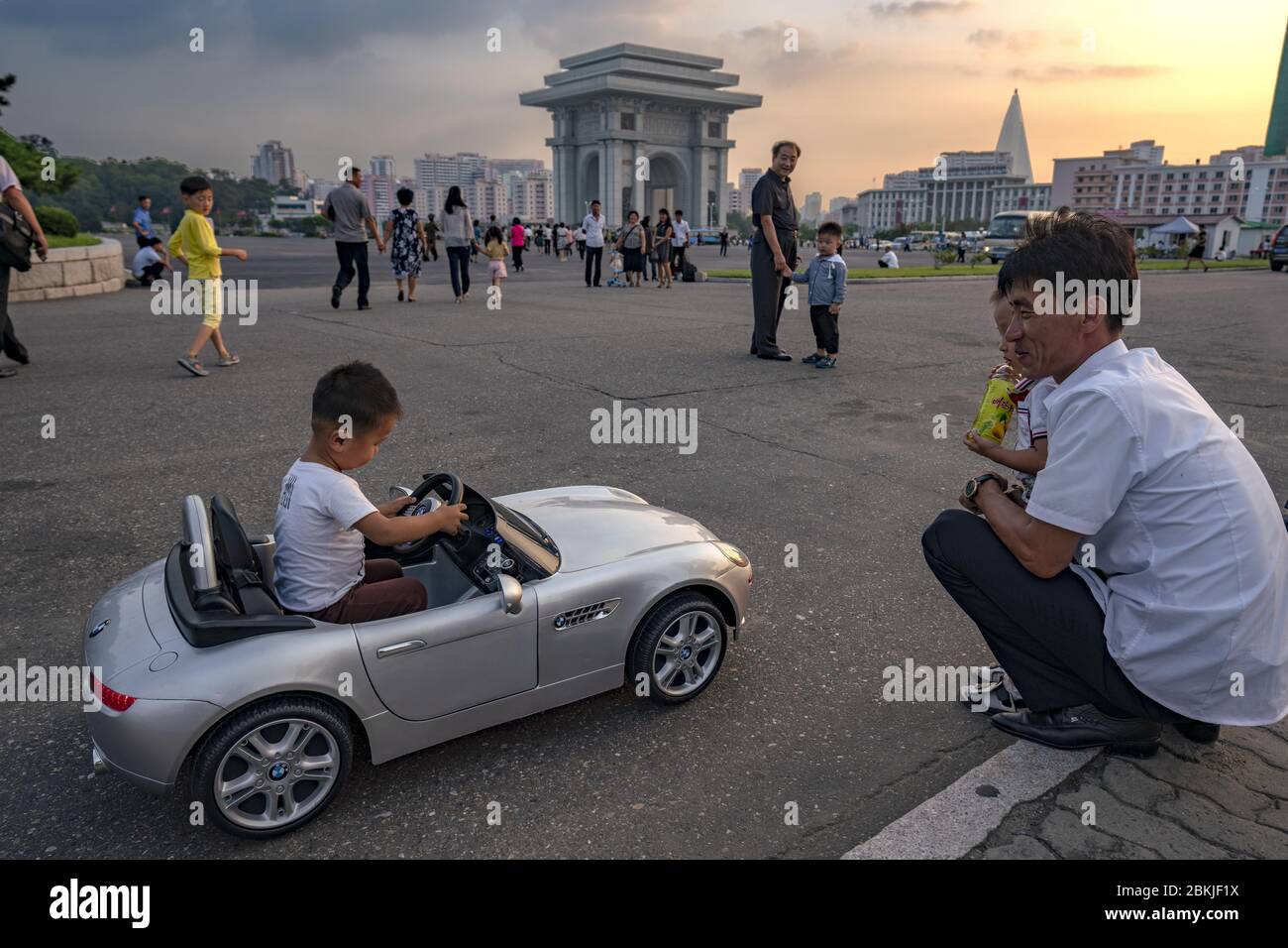 Corea del Nord, Pyongyang, bambino che gioca con una BMW cablati davanti all'Arco di Trionfo Foto Stock