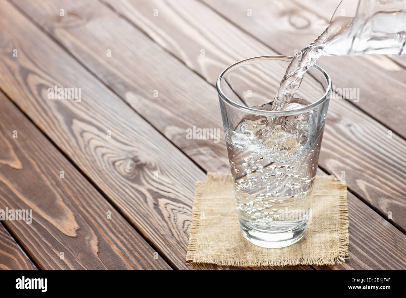 acqua che si versa dalla caraffa nel bicchiere Foto Stock