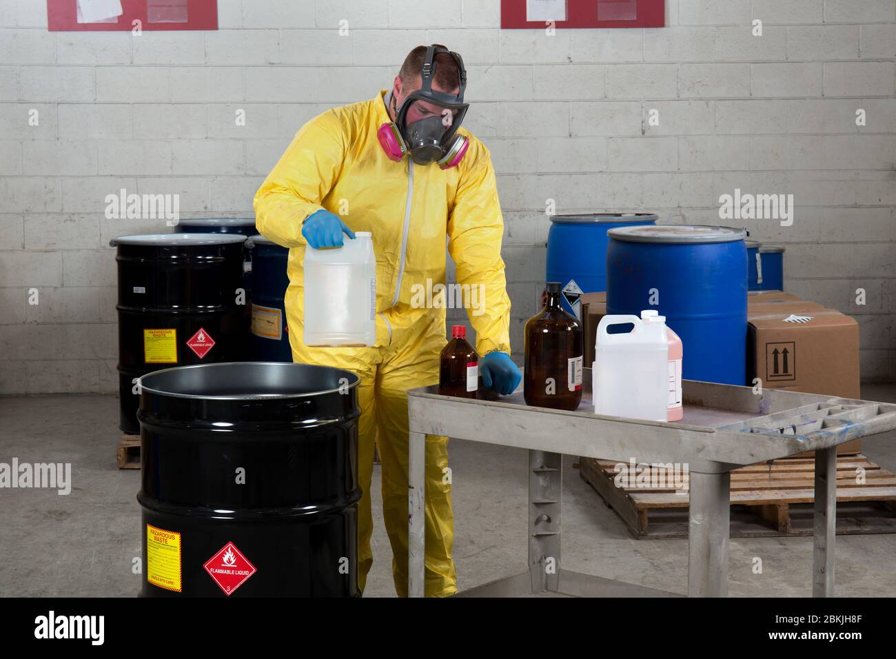 Un lavoratore in abito da nocciola dispone di sostanze chimiche pericolose Foto Stock