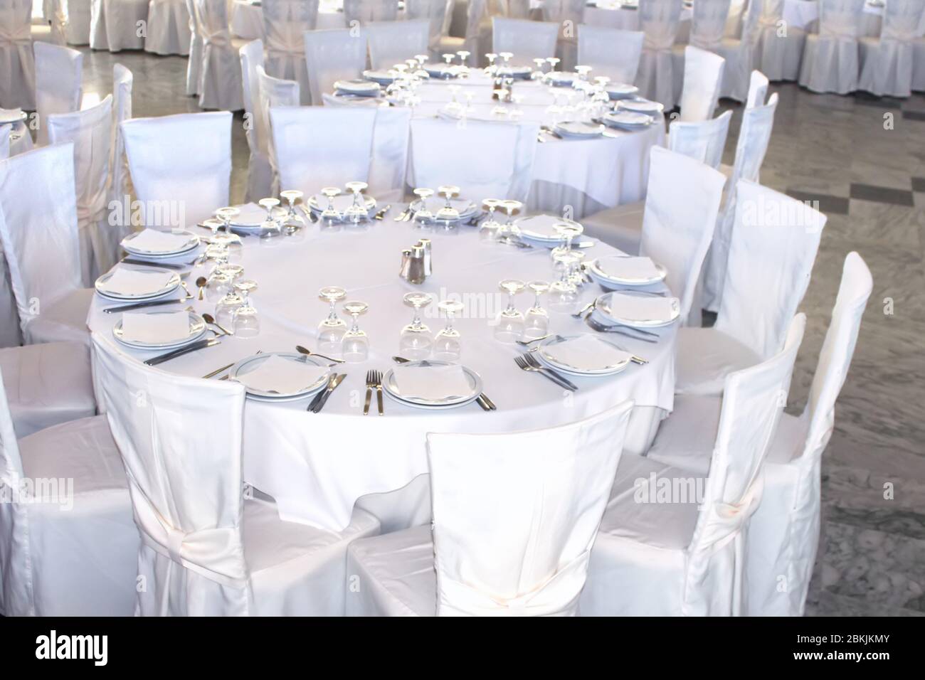 Tavoli rotondi coperti da tovaglia bianca e sedie coperte da una copertina  bianca. Tutto è preparato per un banchetto Foto stock - Alamy