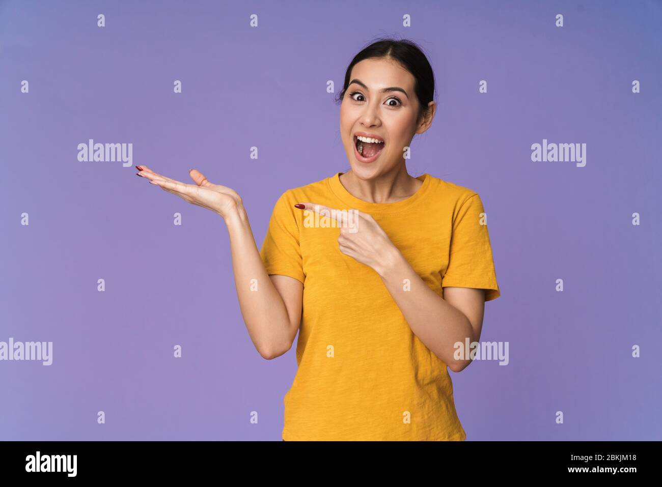 Allegro giovane bella sportivo donna in piedi isolato su sfondo viola, presentando spazio copia Foto Stock