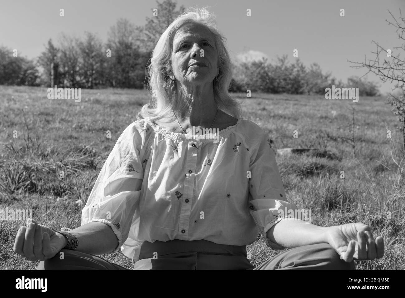 Europa, Lussemburgo, Insenborn, attraente donna anziana meditata vicino Lac Sûre Foto Stock