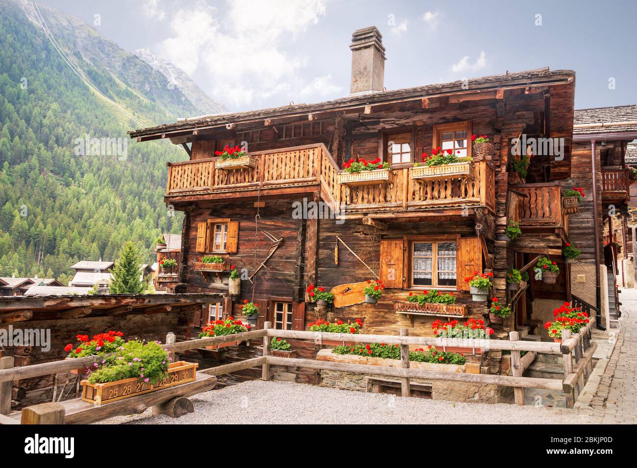 Bella casa in legno decorata con gerani sui balconi nel pittoresco villaggio alpino svizzero Grimentz, comune di Anniviers, cantone di va Foto Stock