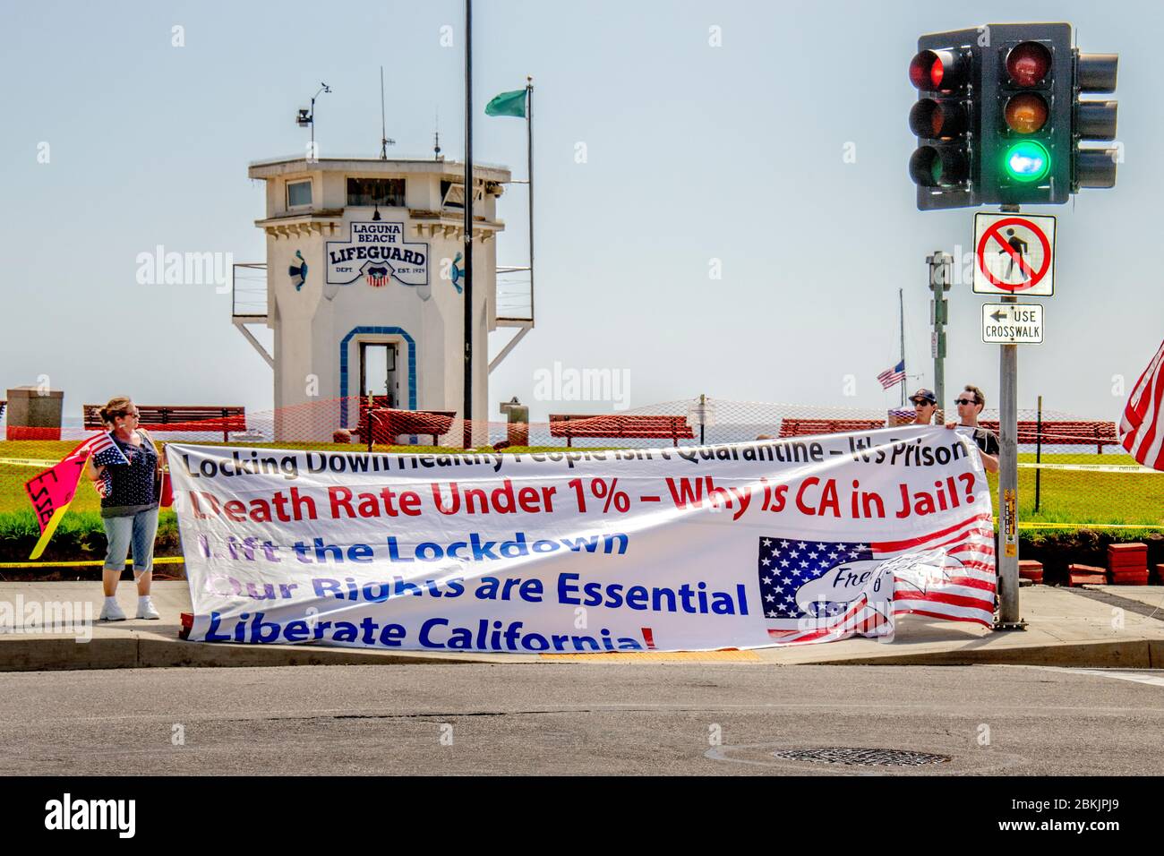 Colpendo una posa patriottica, i manifestanti multirazziali che si oppongono il governatore della California Gavin Newcom blocco a livello statale per combattere il coronavirus/COVID-19 pandemic riunirsi sulla Pacific Coast Highway a Laguna Beach, CA. Foto Stock