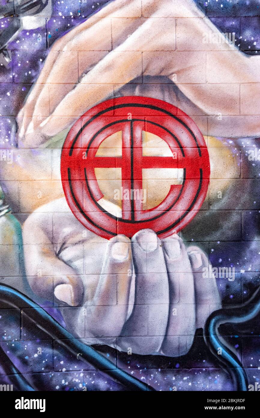 Graffiti arte di due mani grandi che tiene un piccolo simbolo circolare rosso simile al segno astrologico della terra Foto Stock