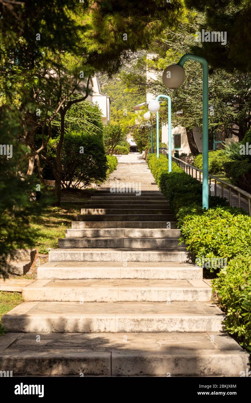 Bol, Croazia, 10 settembre 2019. Lunghe scale con alberi e verde vicino al viale sull'isola di Brac in Dalmazia. Lanterne moderne accanto al percorso Foto Stock