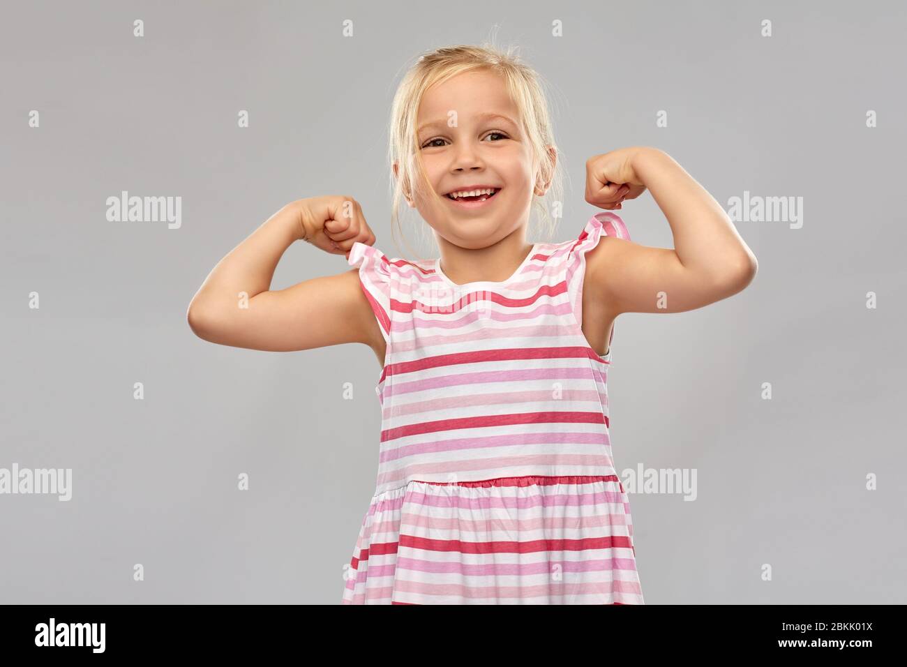 sorridente bambina che mostra il suo potere Foto Stock