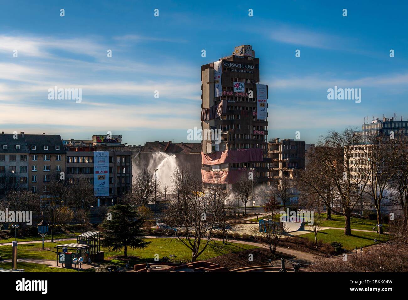 Spazzatura di un edificio assicurativo a Dortmund, Germania. Un’alta fontana d’acqua si eleva accanto alla torre di uffici ancora in piedi, destinata a legare la polvere sollevata dal crollo. A questo punto, la torre assicurativa Volkswohl Bund non mostra danni visibili sulla sua facciata superiore Foto Stock