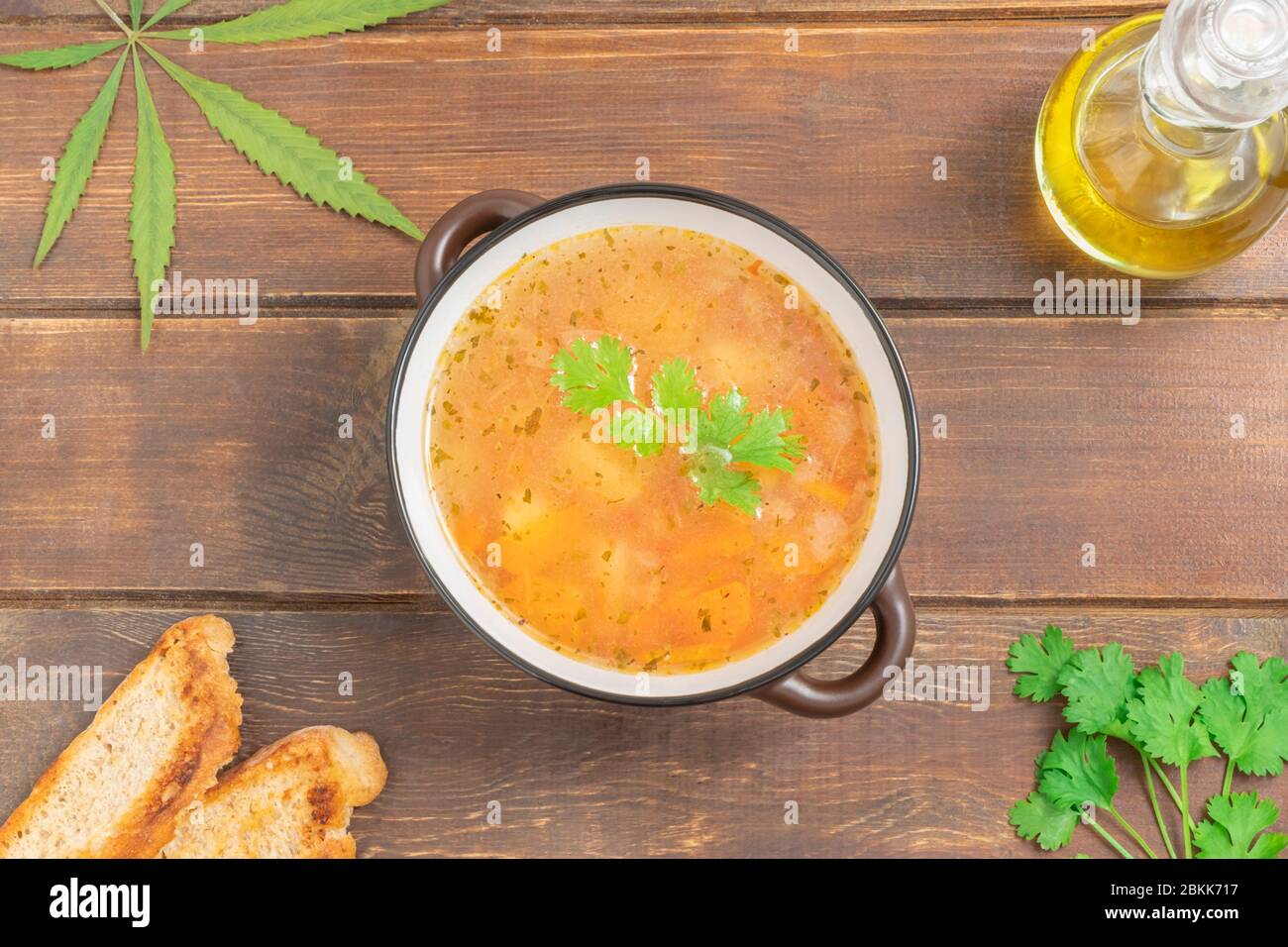 Zuppa di verdure infusa di cannabis in una ciotola su un tavolo di legno, vista dall'alto con spazio per il testo Foto Stock