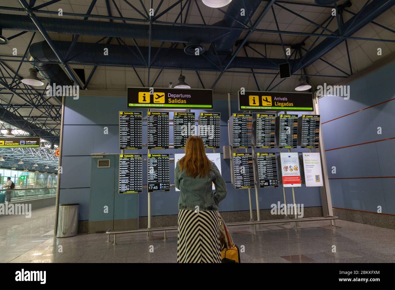 Donna che guarda la scheda elettronica Partenze e arrivi all'aeroporto di Madrid, Spagna Foto Stock