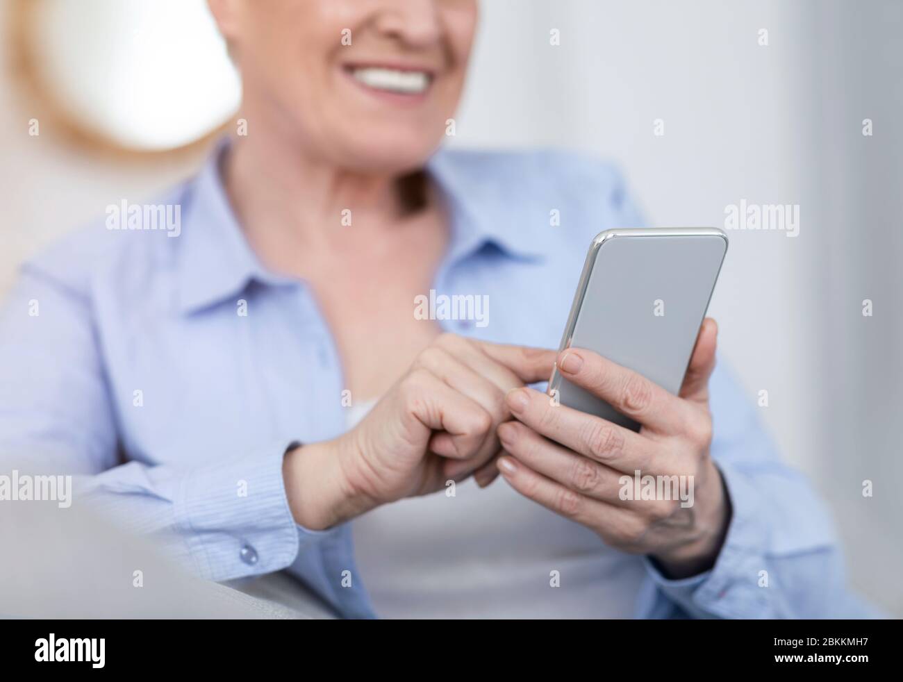 Tecnologie per anziani. Smartphone moderno nelle mani di una donna anziana Foto Stock